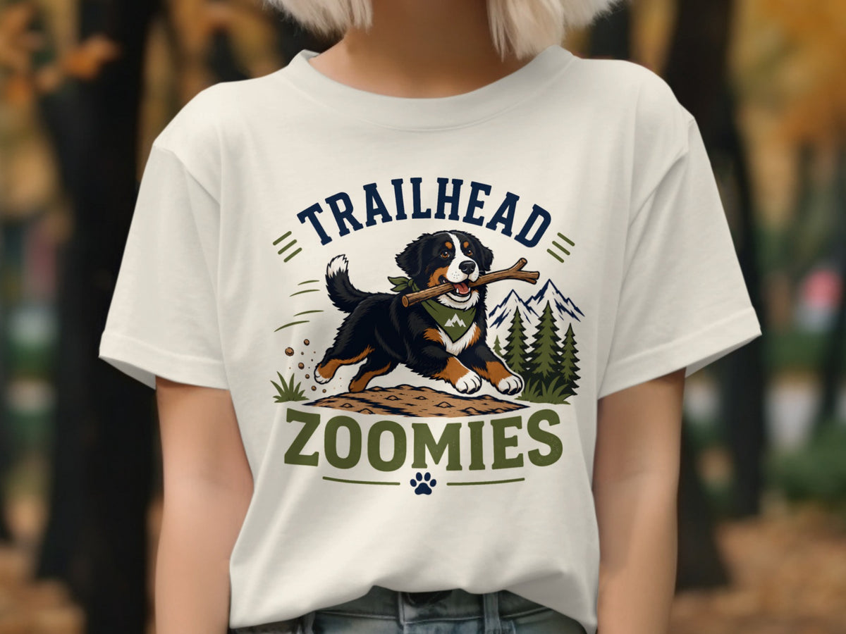 Bernese Mountain Dog with stick on t-shirt that says "TRAILHEAD ZOOMIES."