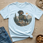 Light blue t-shirt with a graphic of a dachshund wearing a backpack on a mountain.