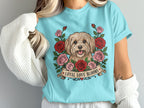 Light blue t-shirt featuring a dog surrounded by pink and red roses with banner text "LOYAL LOVE BLOOMS".