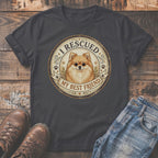Dark t-shirt with a circular graphic featuring a Pomeranian dog and text "I RESCUED MY BEST FRIEND."