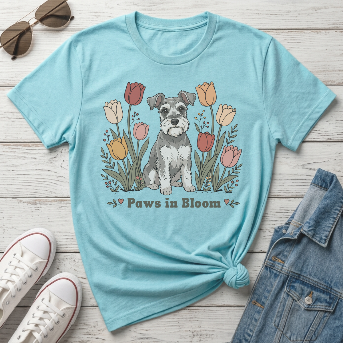 Light blue t-shirt with a schnauzer dog illustration surrounded by tulips and the text "Paws in Bloom".