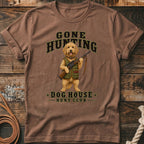 Brown t-shirt with a cartoon dog holding a rifle, text reads "GONE HUNTING" and "DOG HOUSE HUNT CLUB".