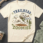 Cream t-shirt with "Trailhead Zoomies" graphic of a dog carrying a stick in mountains.