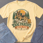 Yellow t-shirt with German Shepherd graphic, text "Dog Parent Social Club," and forest scene.