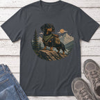 Dachshund wearing backpack on rock with mountain and forest background.
