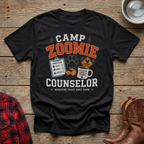 Black t-shirt with "Camp Zoomie Counselor" and graphics of a clipboard, paw print, and coffee mug.