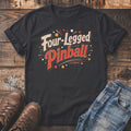 Black t-shirt with "Four-Legged Pinball" text, jeans, and boots on a wooden background.