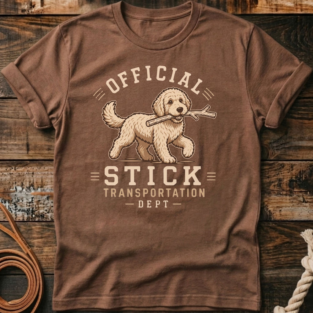Brown t-shirt with graphic of dog carrying a stick and text "Official Stick Transportation - Dept"
