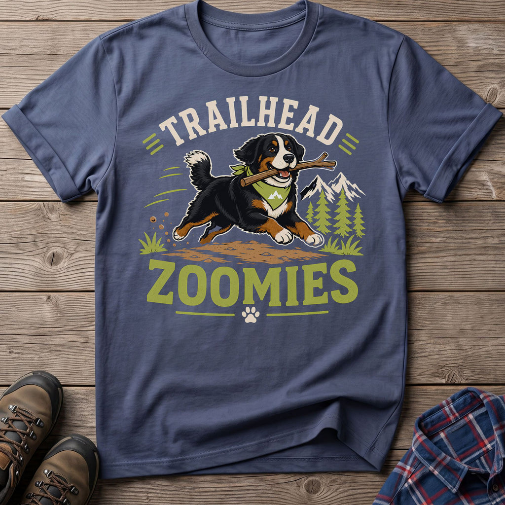 Bernese mountain dog with stick, text "TRAILHEAD ZOOMIES" on a blue t-shirt.