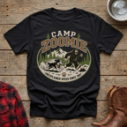 Black t-shirt with "Camp Zoomie" graphic of Bigfoot chasing a dog with text "Unexplained Speed Since 1987".