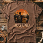 Brown t-shirt with "Dog Dad" text and illustration of man and dog at sunset.