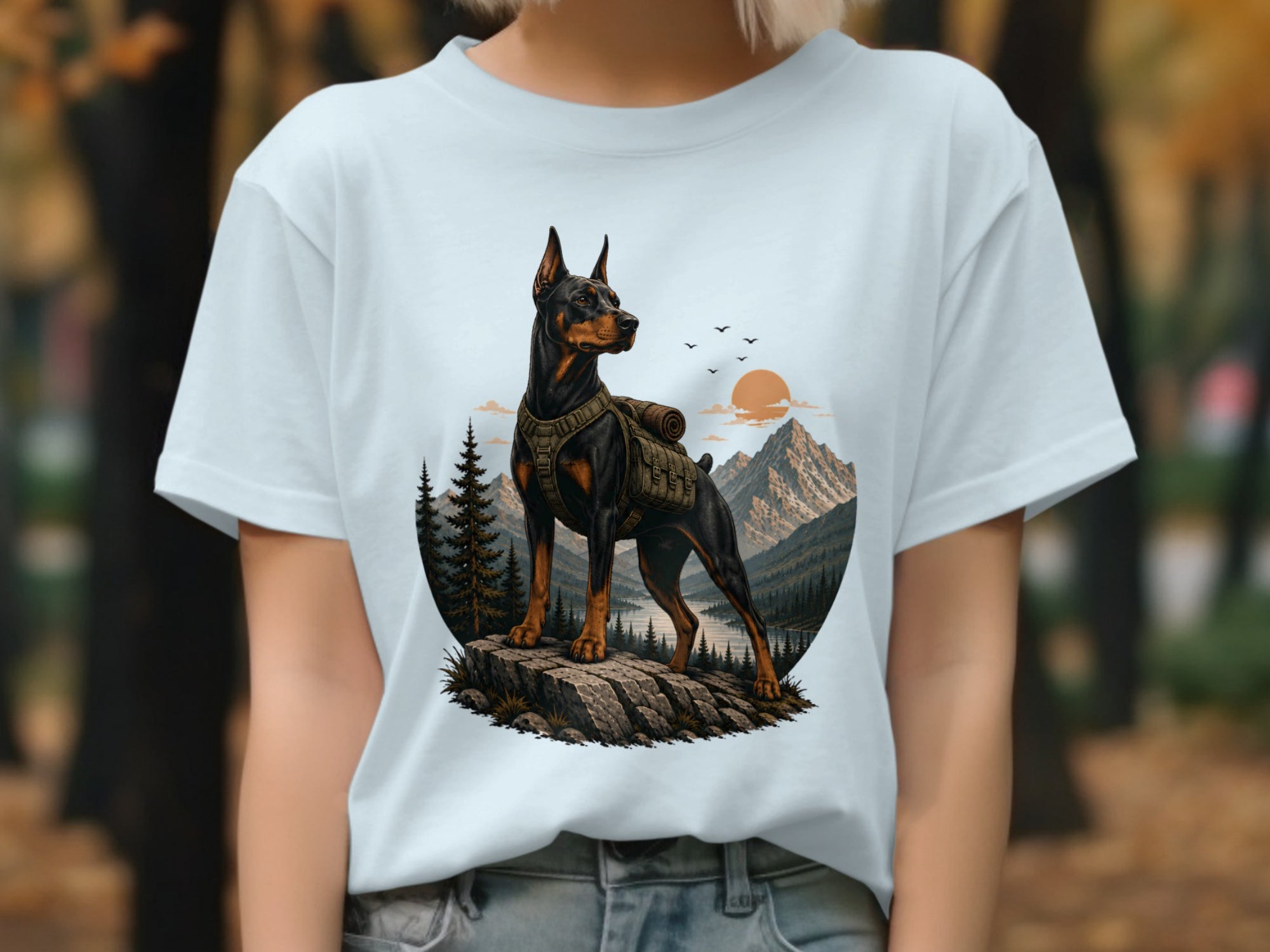 Doberman wearing backpack on rocky outcrop with mountain and lake background.