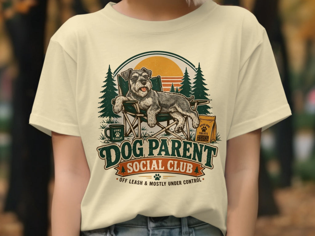 Schnauzer relaxing in chair, "Dog Parent Social Club" text, trees, sunset.