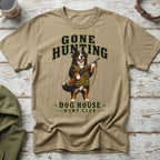 Bernese Mountain Dog wearing hunting vest holds a rifle with "Gone Hunting Dog House Hunt Club" text.