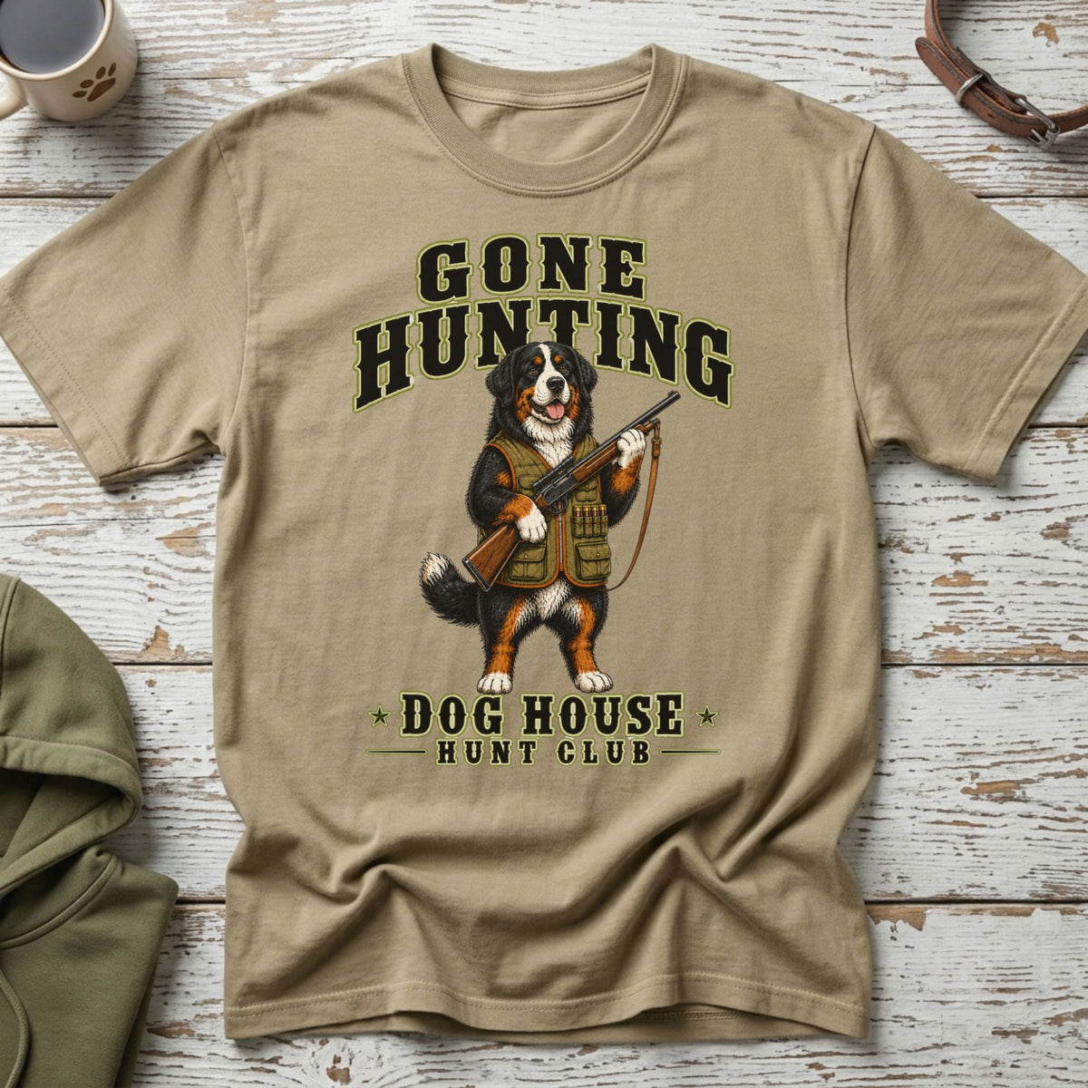 Bernese Mountain Dog wearing hunting vest holds a rifle with "Gone Hunting Dog House Hunt Club" text.
