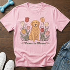 Pink t-shirt with a golden retriever sitting among tulips, reads "Paws in Bloom".