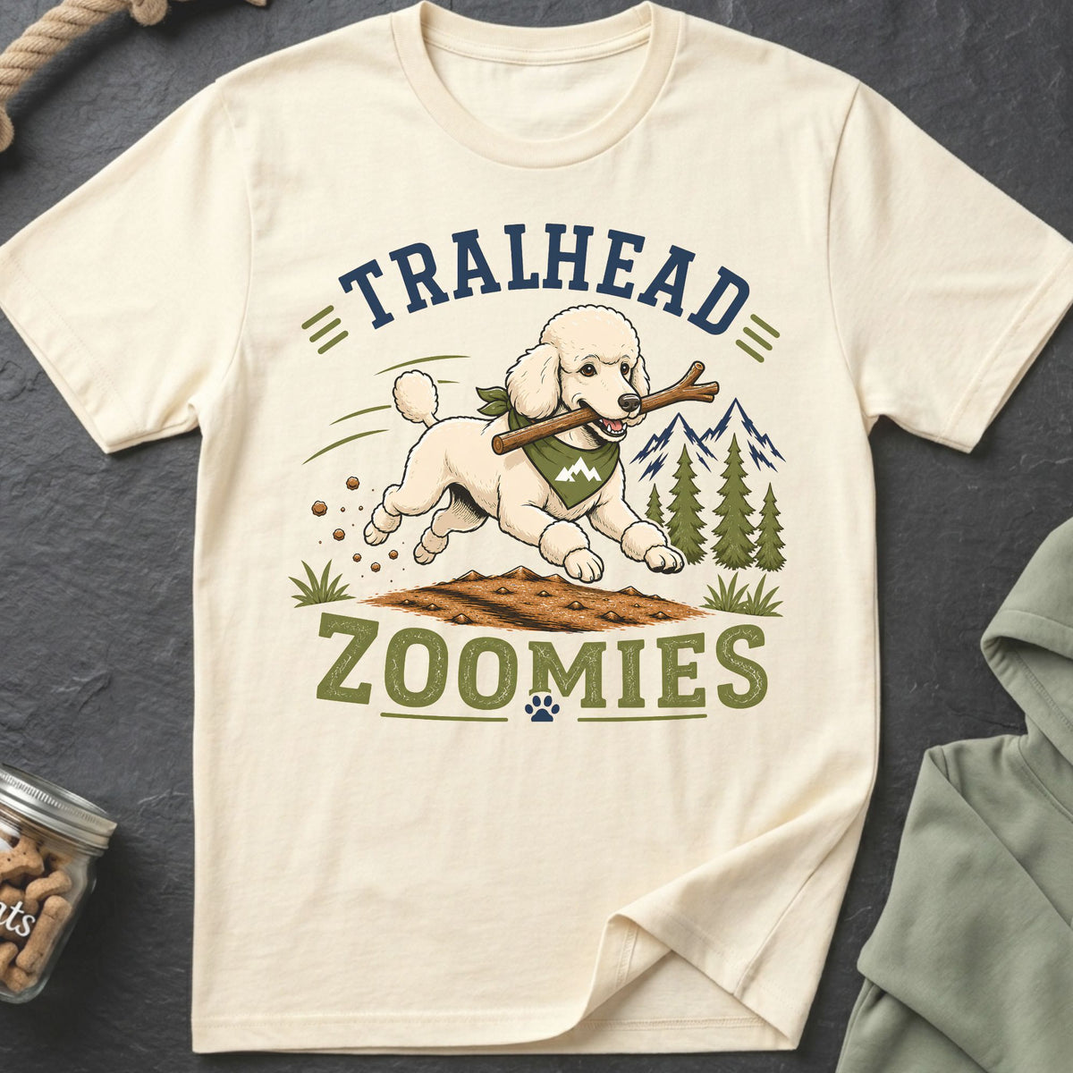 Cream t-shirt with graphic of a poodle running with a stick, mountains, and text "TRAILHEAD ZOOMIES".
