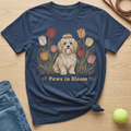 Navy t-shirt with a shaggy dog sitting among colorful tulips and text that reads "Paws in Bloom."