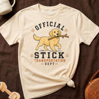 Cream t-shirt with a golden retriever carrying a stick, text reads "OFFICIAL STICK TRANSPORTATION DEPT".