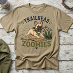 French bulldog running with stick, "TRAILHEAD ZOOMIES" text, pine trees, and mountains.
