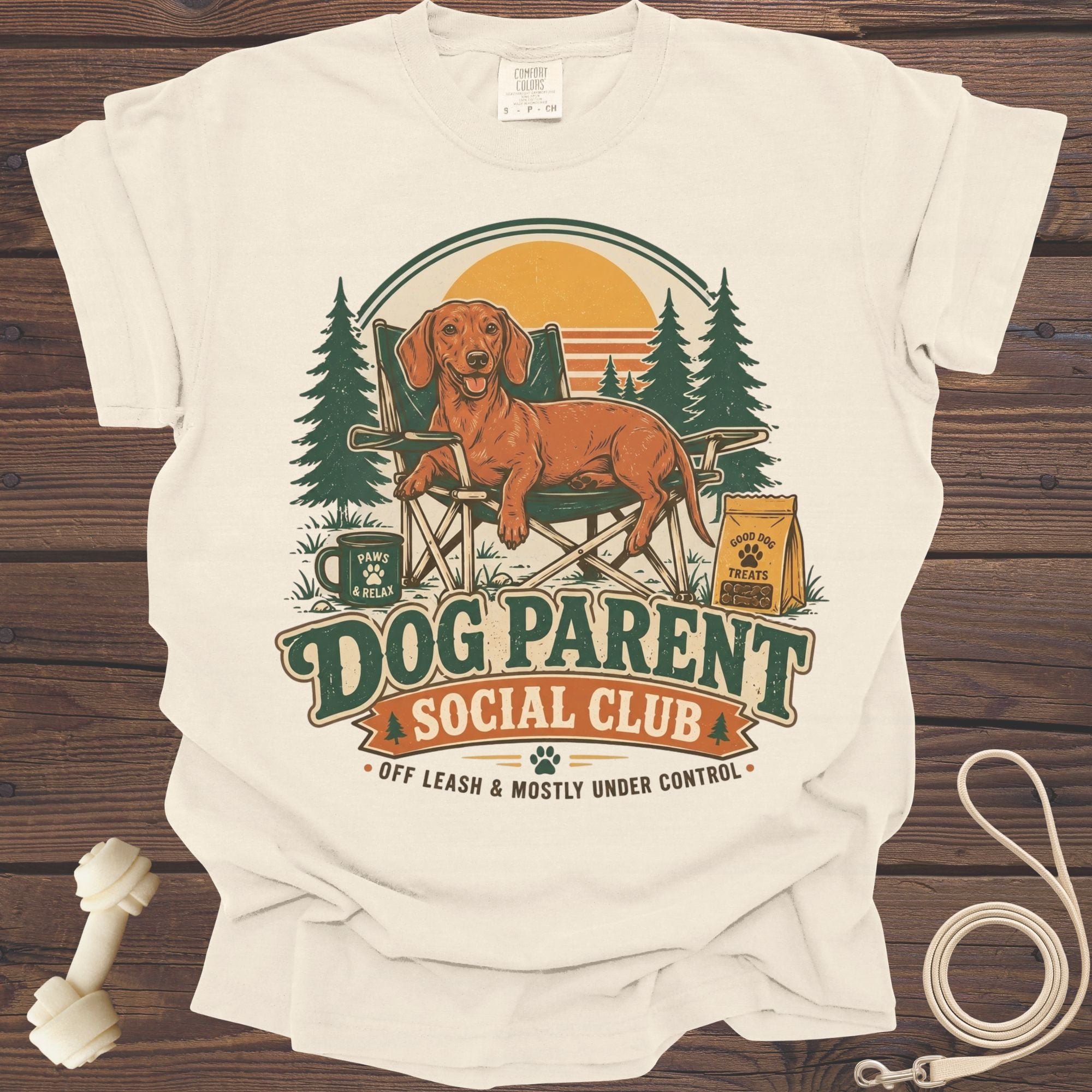 Cream t-shirt with a dachshund in a camping chair, text "Dog Parent Social Club."