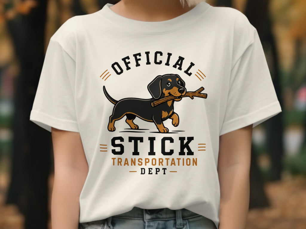 White t-shirt graphic with dachshund carrying a stick, "OFFICIAL STICK TRANSPORTATION DEPT" text.