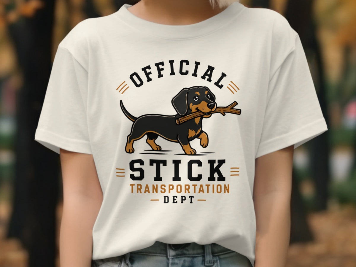 White t-shirt graphic with dachshund carrying a stick, "OFFICIAL STICK TRANSPORTATION DEPT" text.