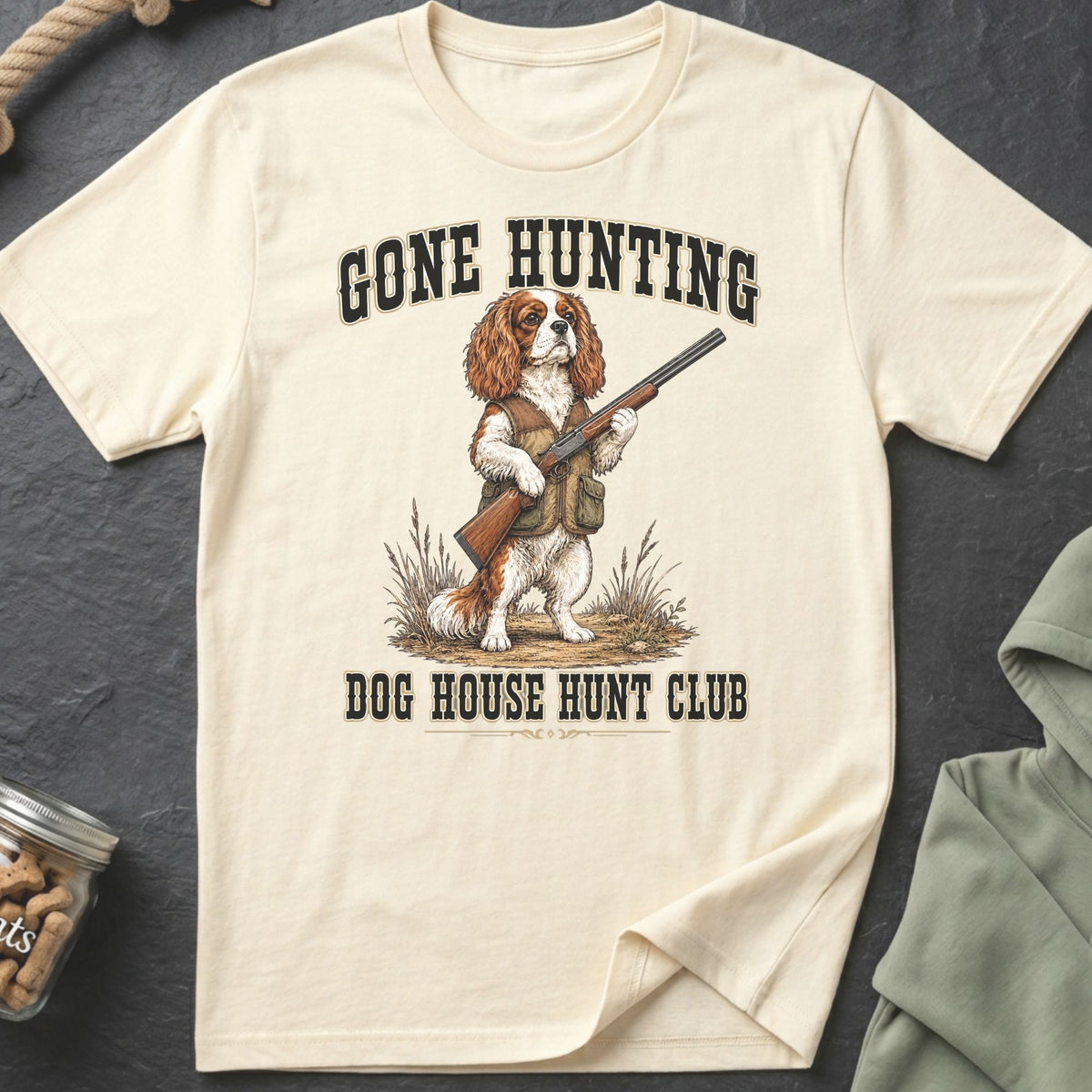 Cream t-shirt with a Cavalier King Charles Spaniel holding a shotgun, text reads Gone Hunting Dog House Hunt Club.