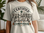 Light beige t-shirt with "Certified Pre-Loved Chaos Companion" text and paw print.