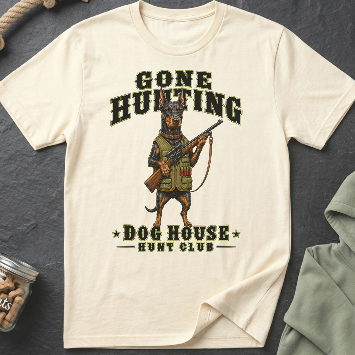 Cream t-shirt with a Doberman holding a rifle and the text "Gone Hunting Dog House Hunt Club".
