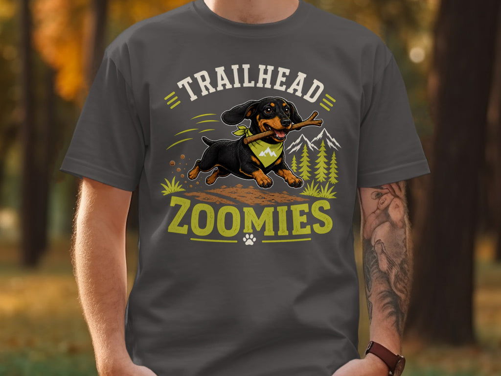 Dachshund with stick on shirt text "TRAILHEAD ZOOMIES" and mountain graphics.