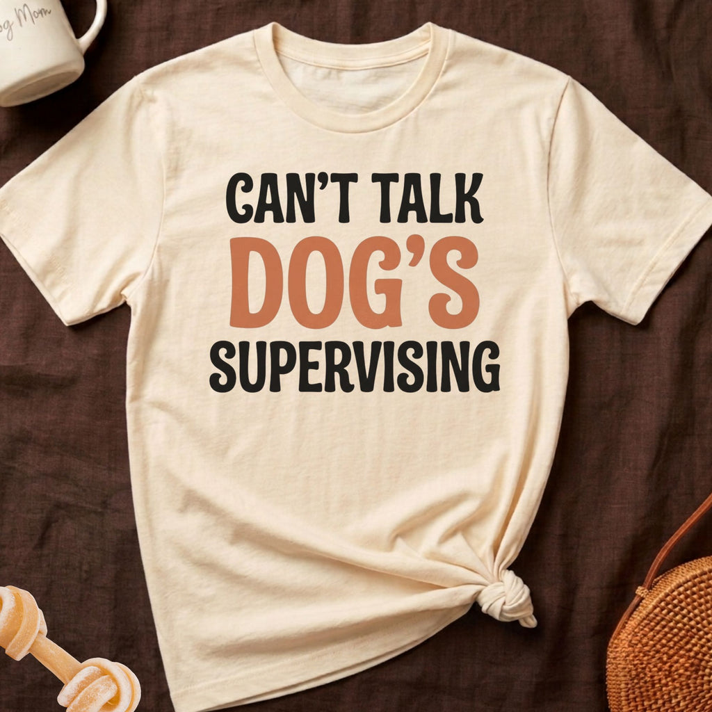Cream t-shirt with black and orange text "CAN'T TALK DOG'S SUPERVISING".