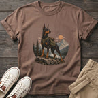 Brown t-shirt with a Doberman wearing a backpack in a mountain landscape.