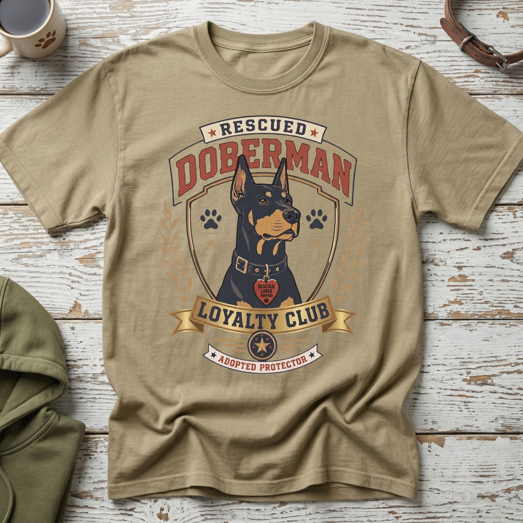 Tan t-shirt with a Doberman dog graphic that says "Rescued Doberman Loyalty Club Adopted Protector."