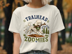 White t-shirt with a poodle running with a stick, text "TRAILHEAD ZOOMIES"
