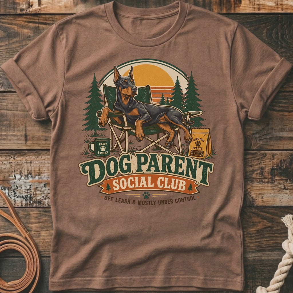 Doberman on chair with "Dog Parent Social Club" text and outdoor scene.