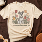 Cream t-shirt with a schnauzer in front of blooming tulips and text "Paws in Bloom".