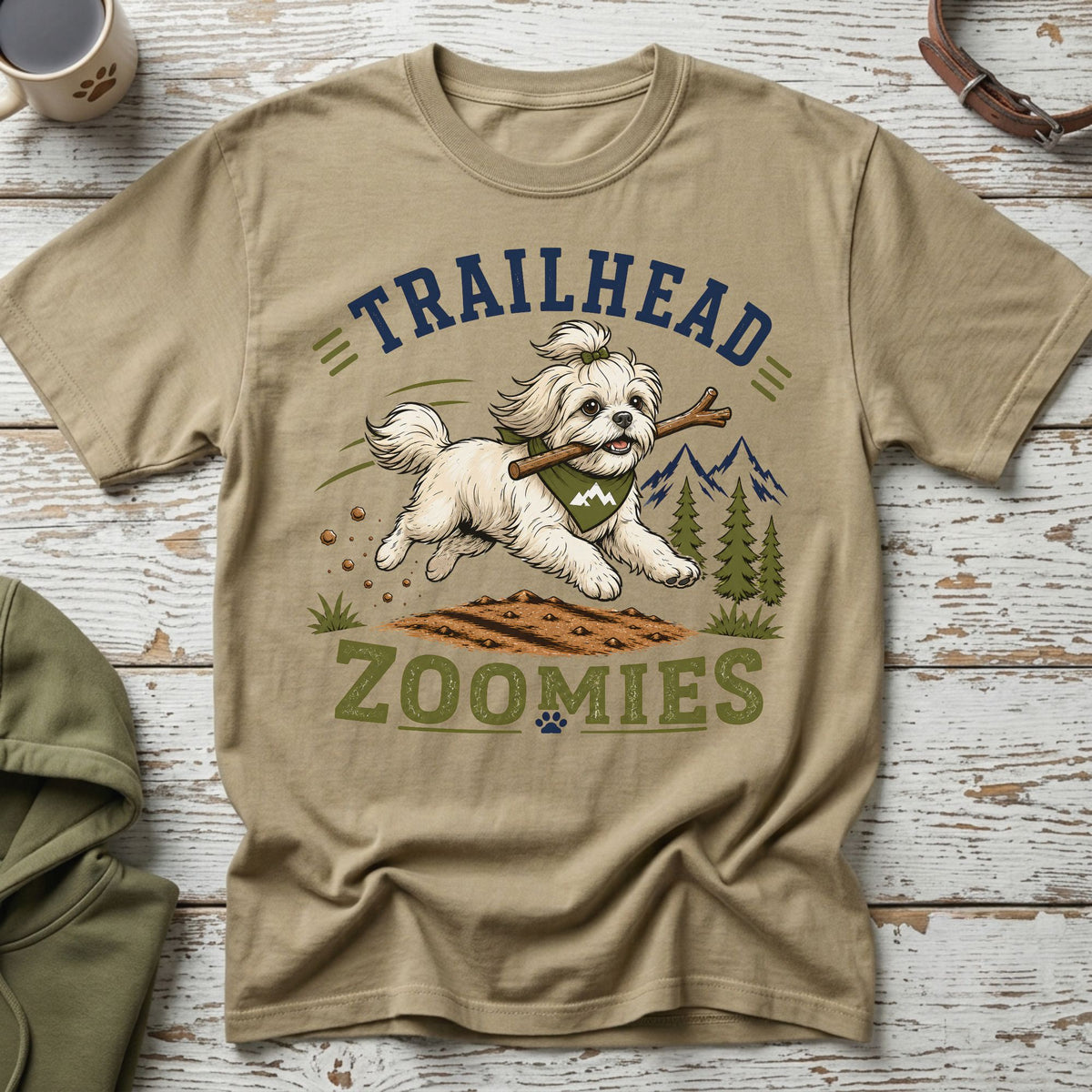 Tan t-shirt with "Trailhead Zoomies" text and a white dog holding a stick.