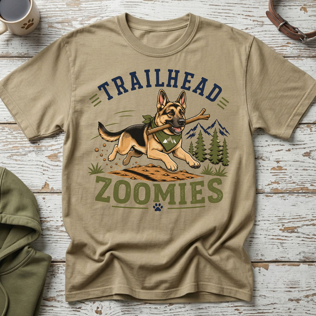 German Shepherd with stick on t-shirt reading "Trailhead Zoomies" with mountains and trees.