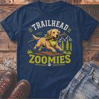 Yellow lab running with stick on shirt that says "TRAILHEAD ZOOMIES".