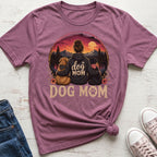 T-shirt graphic of a woman with two dogs, mountains, and sunset, saying "DOG MOM".
