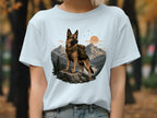 German Shepherd with backpack on rock, mountains, river, and sun.