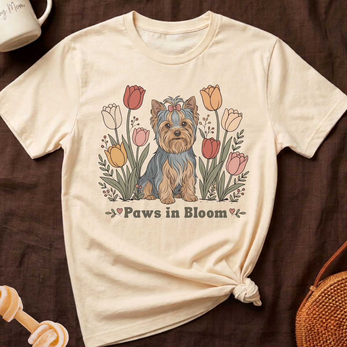 Cream t-shirt with a Yorkshire Terrier sitting among colorful tulips and the text "Paws in Bloom".