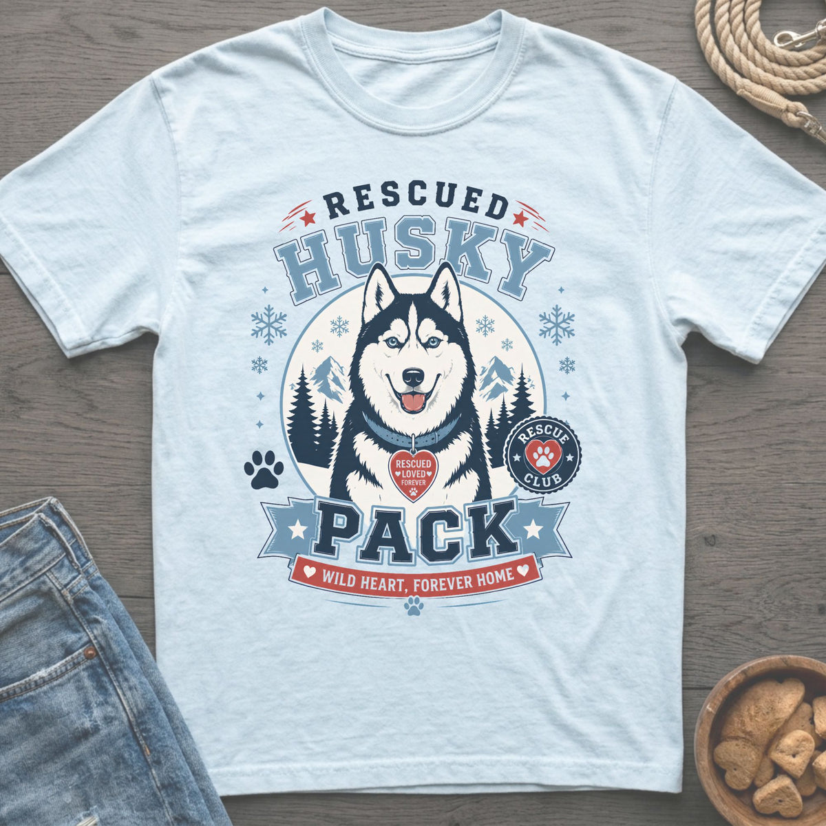 Light blue t-shirt graphic: Rescued Husky Pack with dog, mountains, and snowflakes.