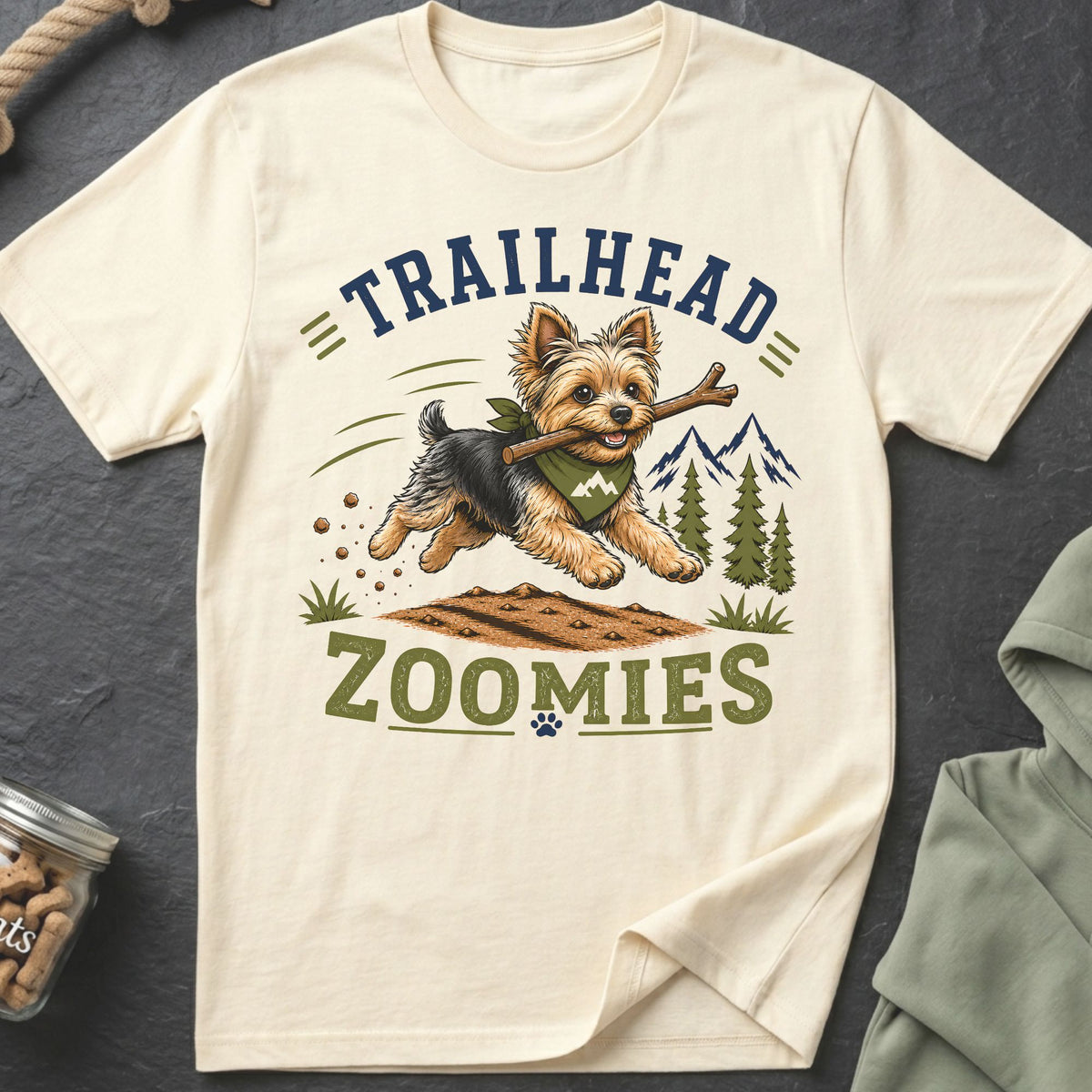 Yorkshire Terrier with stick on shirt reading "Trailhead Zoomies" with mountains.