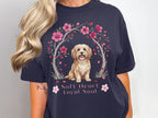 Dark navy t-shirt with a drawing of a fluffy dog surrounded by pink blossoms and text.