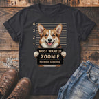 Corgi holding a "Most Wanted Zoomie Reckless Speeding" sign in front of a mugshot backdrop on a dark t-shirt.