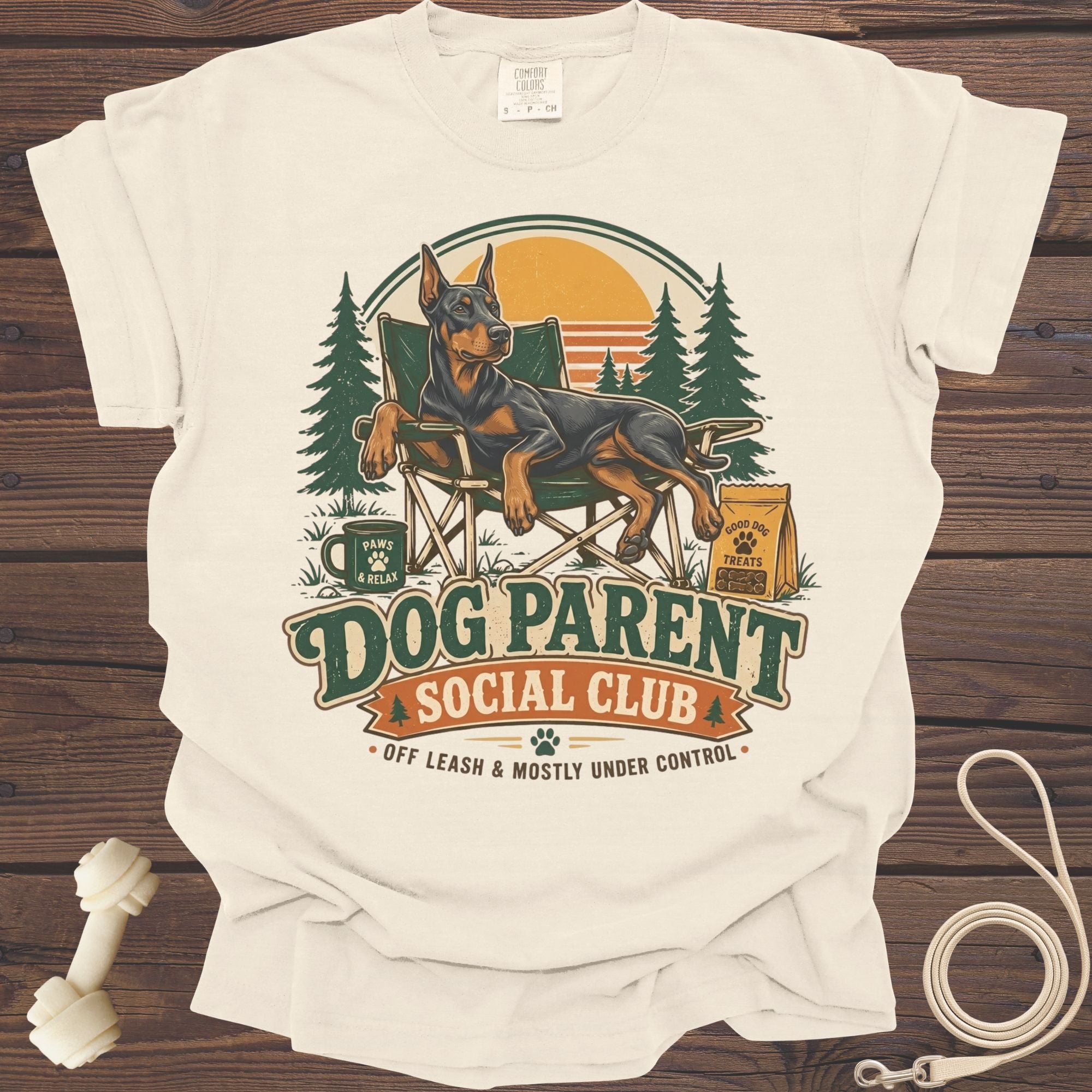 Cream t-shirt with Doberman relaxing in a chair, "Dog Parent Social Club" text.