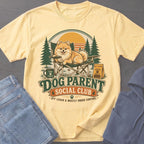Yellow t-shirt with a Pomeranian dog relaxing in a camping chair, text reads "Dog Parent Social Club".