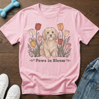 Pink t-shirt with a dog sitting among tulips and the text "Paws in Bloom".